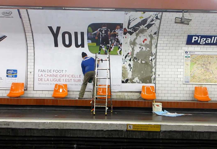 COLLEUR D'AFFICHES DANS LE MÉTRO PARISIEN